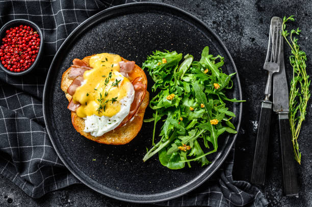 istock Breakfast Burger with bacon, egg Benedict, hollandaise sauce on brioche bun. Black background. Top view 1237105923