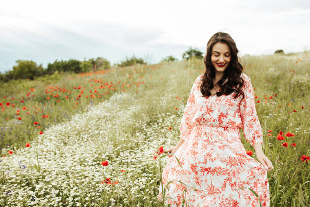 カモミールの白いフィールドで若い女性の美しさ - floral dress ストックフォトと画像