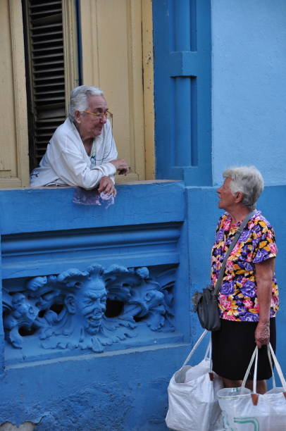So much of Cuban life takes place on the city streets: negotiating with ambulant vendors, gossiping and board games with neighbors, playing music for passersby, etc. Here two neighbours chat through a window. Photos taken in Santiago de Cuba in January 2017.
