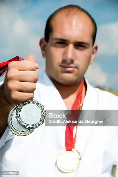 Człowiek W Biały Karate Garnitur I Przytrzymując Medal - zdjęcia stockowe i więcej obrazów Srebrny medal