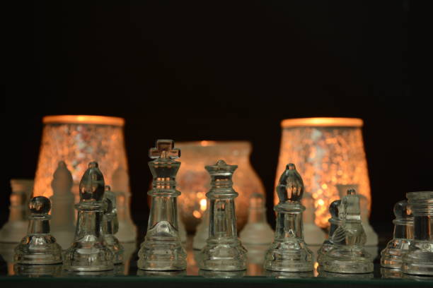 istock Clear glass chess pieces on a glass chessboard isolated on a black background 1237167477
