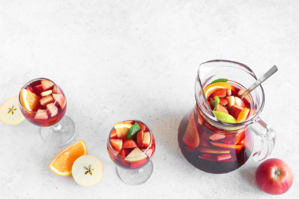 Red Wine Sangria Red Wine Sangria in pitcher and glasses on white table, top view, copy space. Homemade refreshing drink - fruit sangria or punch. green apple slice overhead stock pictures, royalty-free photos & images