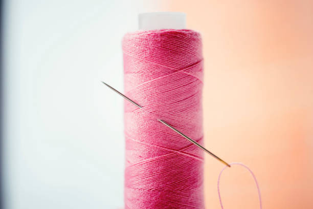 istock Pink spool of thread and a needle in it, side view, macro photo. 1237172441