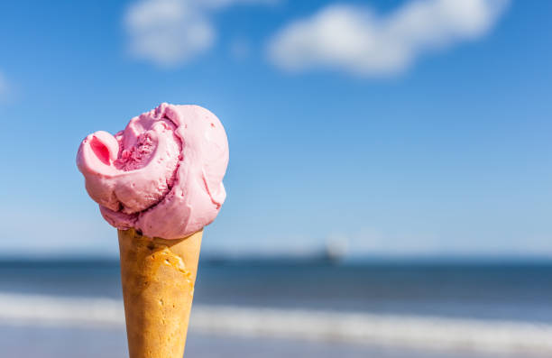 istock Black Cherry Ice-cream cone with blue sea, blue sky and white fluffy clouds on a bright sunny summers day 1237185688