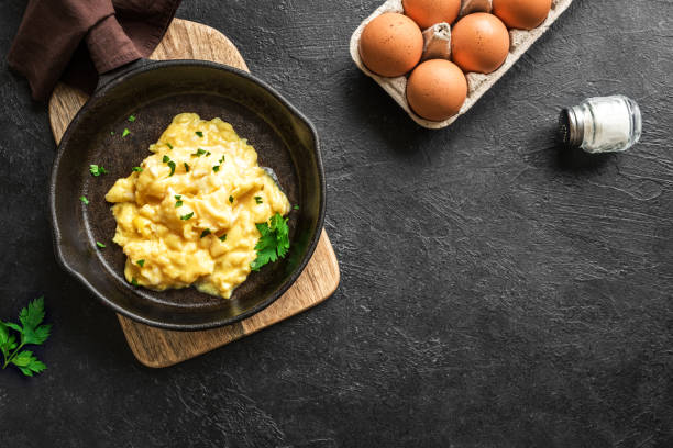 Scrambled Eggs Scrambled Eggs on frying pan for healthy breakfast or brunch, top view, copy space. Homemade meal recipe - scrambled eggs on black background. Scrambled Eggs stock pictures, royalty-free photos & images