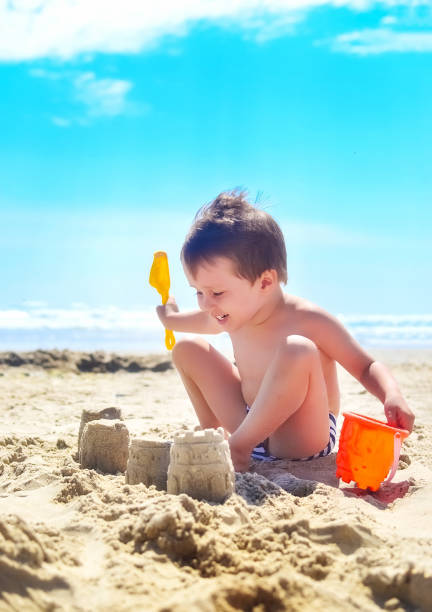 istock a boy plays with sand and builds sand castles on the seashore. summer mood 1237204426