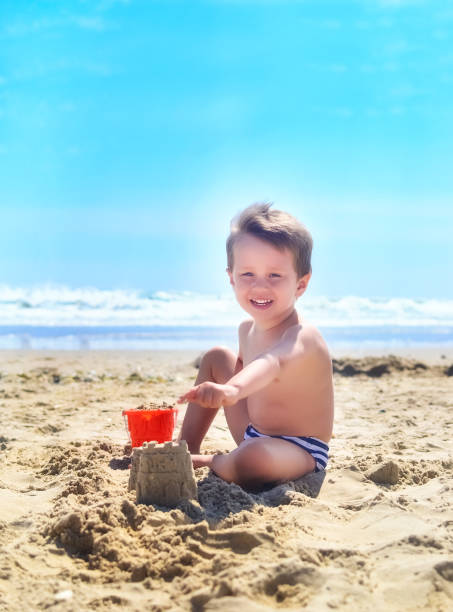 istock a boy plays with sand and builds sand castles on the seashore. summer mood 1237204960