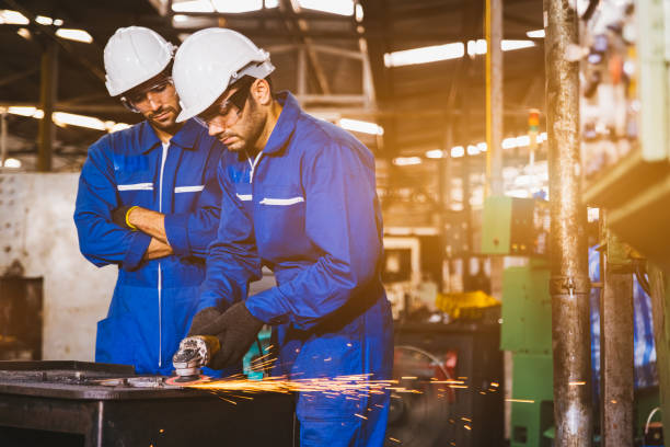istock Group of technician industrial engineers wearing safety uniform and safety helmet cutting metal part using hand angle grinder machine. Large industrial factory background. 1237205487