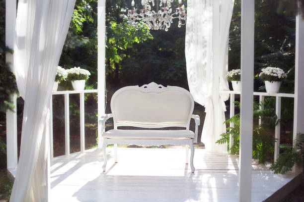 istock In the garden there is terrace on which a white sofa in style of Provence or rustic. Beautiful sofa is on podium Outdoor. Summer gazebo with white curtains. Wedding decorations. Romantic alcove. 1237238191