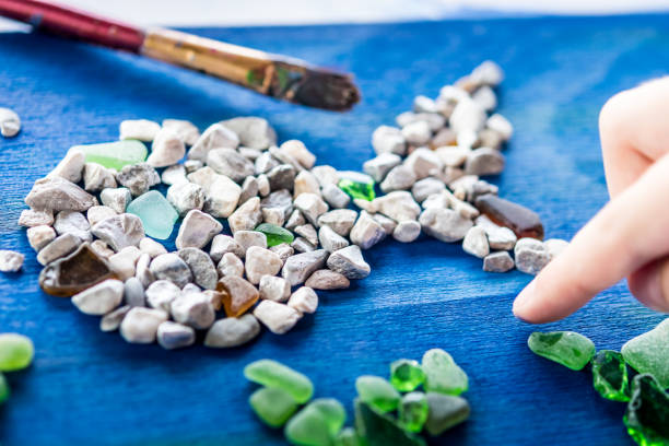 close up girl hands making summer mosaic com pequenas pedras e copos de mar em tábua azul de madeira - mosaic human hand craft artist - fotografias e filmes do acervo