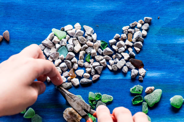 close up girl trabalhando em mosaico de verão colorido usando pequenas pedras e óculos de mar - mosaic human hand craft artist - fotografias e filmes do acervo