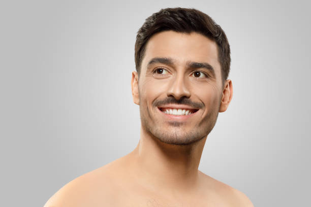 istock Young handsome man with naked shoulders and bristle, looking aside with dreamful smile, thinking of something pleasant, isolated on gray background 1237257804