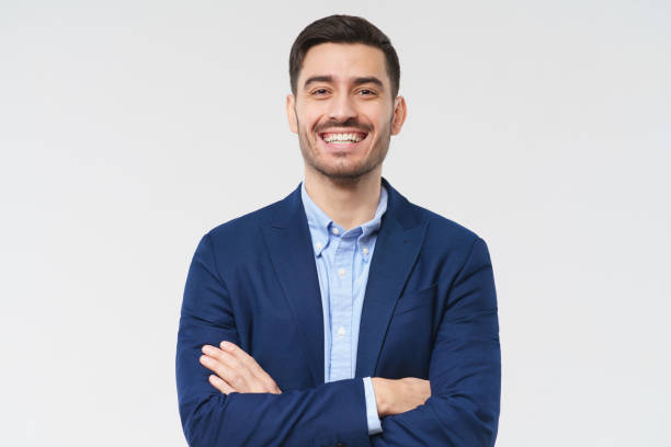 istock Young man dressed in blue suit and shirt, holding arms crossed while looking at camera, laughing happily at joke of friend, isolated on gray background 1237258339