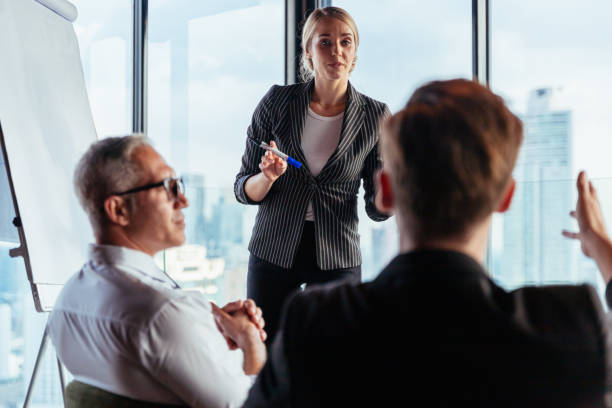 istock Businesswoman coach speaker wear suit give blank flipchart presentation, Speaker presenter consulting training persuading employees client group, Business meeting, seminar, presentation concept. 1237280166