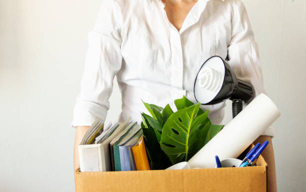 istock lose job concept. Hand holds box of fired worker. In a box they lay documents, folders, a flower, stationery, a table lamp. Unemployment concept 1237296440
