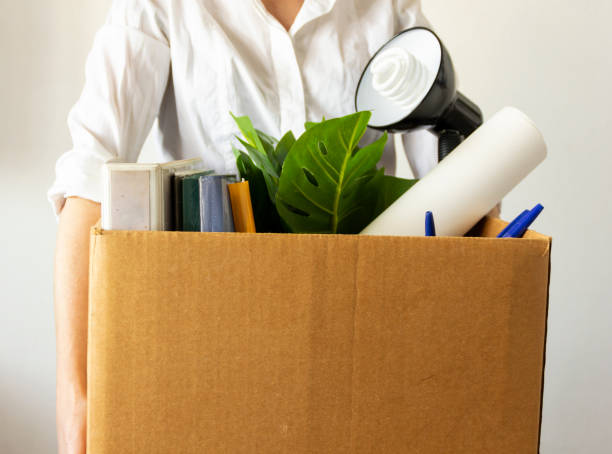 istock lose job concept. Hand holds box of fired worker. In a box they lay documents, folders, a flower, stationery, a table lamp. Unemployment concept 1237296956