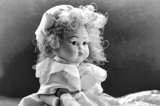 Beautiful vintage porcelain doll black and white portrait with classic dress curly hairs  and sweet glance