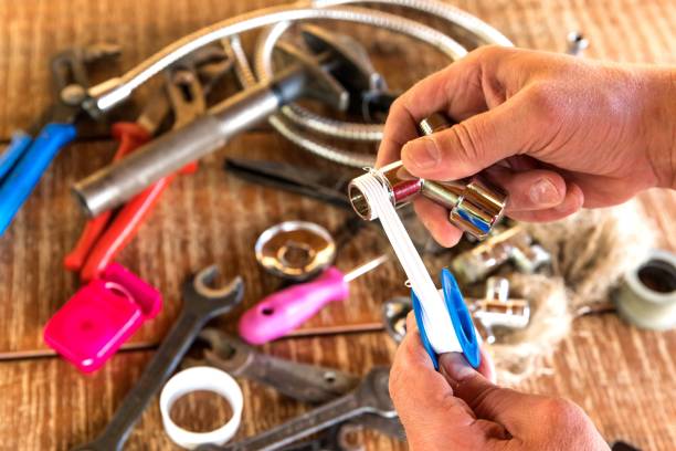 Plumber putting a teflon tape, closeup. Plumber tools on workshop table. Repair of water pipes. Sealing thread Plumber putting a teflon tape, closeup. Plumber tools on workshop table. Repair of water pipes. Sealing thread polytetrafluoroethylene photos stock pictures, royalty-free photos & images