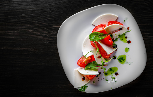 Italian Caprese salad with tomato and cheese in white plate