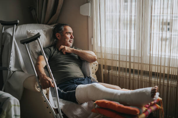 homme avec la jambe cassée à la maison - physical injury men orthopedic equipment isolated on white photos et images de collection