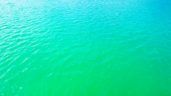 Summer background - turquoise water surface with small waves in the sun light