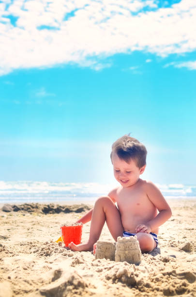 istock a boy plays with sand and builds sand castles on the seashore. summer mood 1237366939
