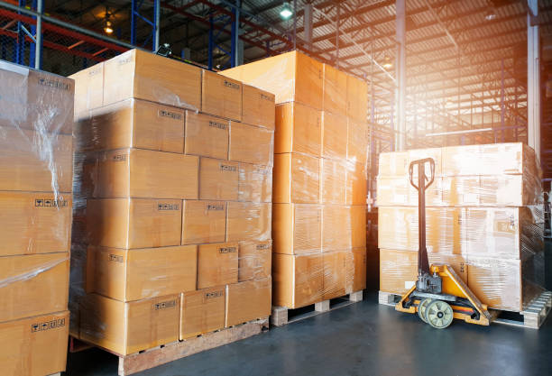 istock Interior of warehouse storage. Stack of shipment boxes on pallets and hand pallet truck 1237399992