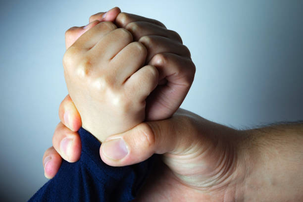 Father roughly holds the hands of his son. Child abuse, domestic violence. stock photo