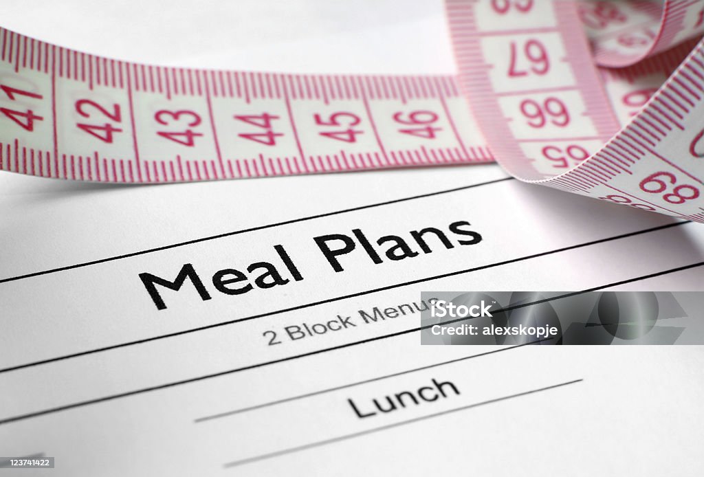 A weight loss meal plan sheet alongside a tape measure Close up of measure tape on meal plan  Adult Stock Photo
