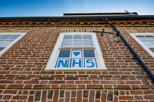 Vista vertical de un letrero casero de Love NHS que se ve unido a una ventana de faja para una casa de pueblo. photo