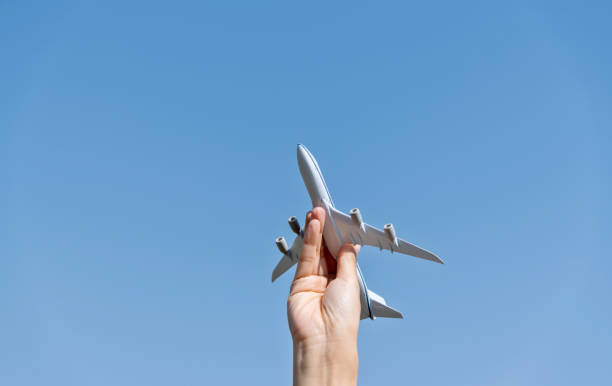 istock Woman hand holding model airplane under blue sky 1237423763