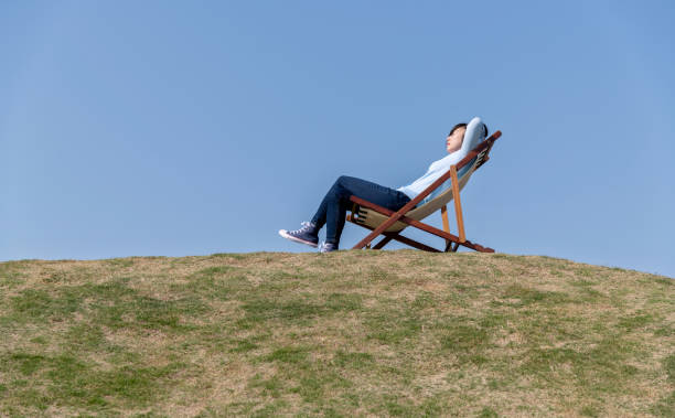 Young woman lying down on deck chair.