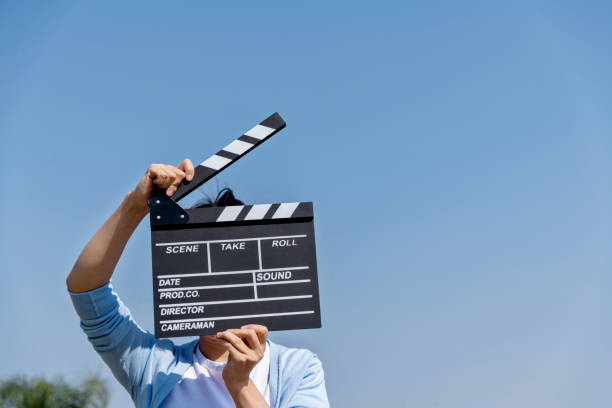 istock Woman hands holding film slate under blue sky 1237443826