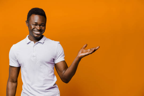 istock Big discount for our customers. Funny black man points right side and smiles on orange background. Smiley people lifestyle. Advertise for online delivery services. Empty place for adver 1237458462