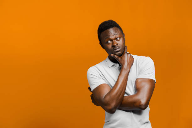 istock Big discount for our customers. Funny black man points right side and grimacing on orange background. Smiley people lifestyle. Advertise for online delivery services. Empty place for adver 1237459493