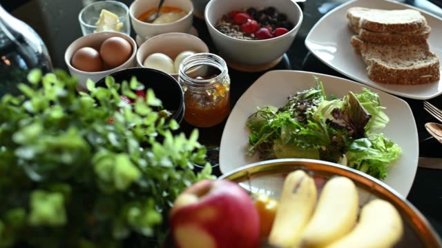 healthy breakfast with fruit orange, strawberry, vegetable, banana, eggs, toasted bread, yogurt apple and jams on dining table
