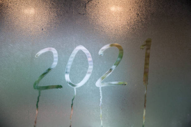 istock A Text 2021 painted on a misted window. write number new year 2021 on misted glass. Heart on a window background. 2021 symbol of new year drawn on the glass. 1237466942