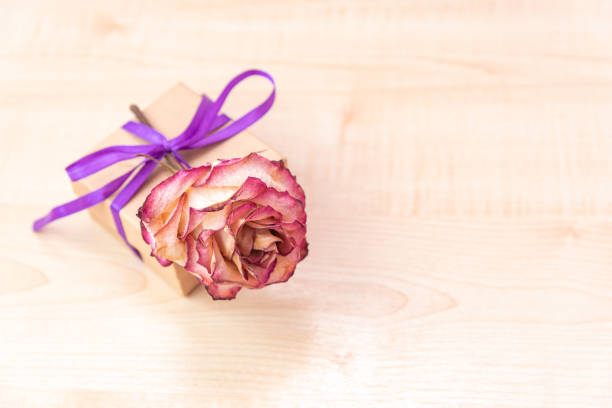 Gift box with a lilac ribbon and a bow on a wooden background. Selective focus.