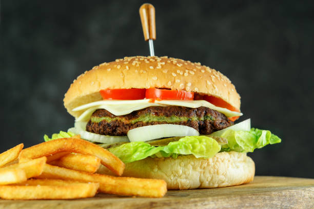 istock Dietary burger with spinach cutlet, cheese and vegetables. Fried potato on the wooden cutting board. 1237467859