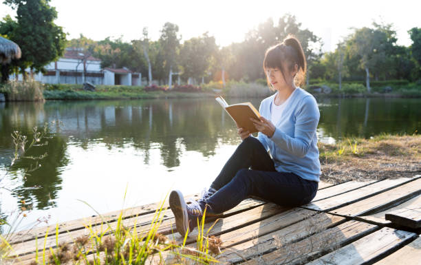 Woman reading a book by the lake.