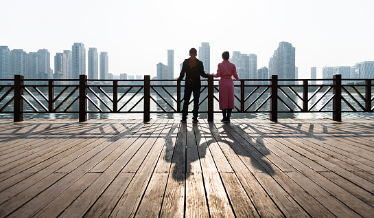 Couple standing on boardwalk by the sea.