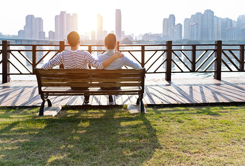 Couple sitting on bench by the sea.