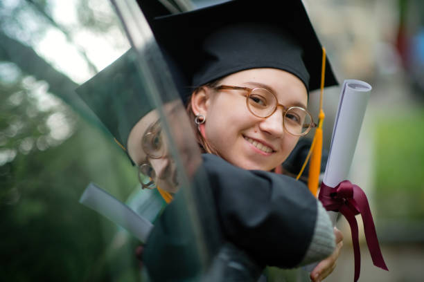 teenage girl wearing graduation gown and cap with diploma in car - university graduation car student imagens e fotografias de stock
