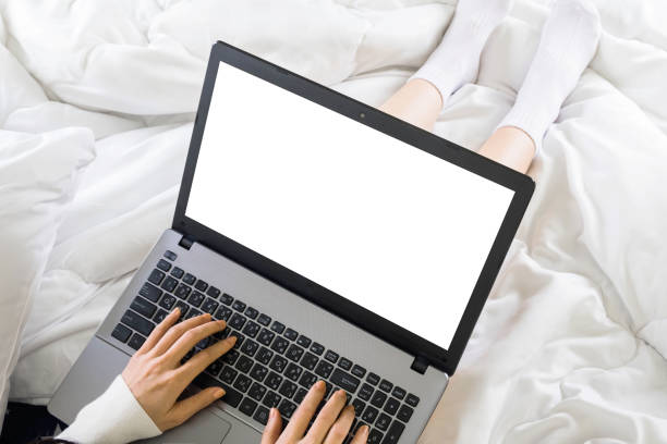 istock woman sitting and typing work with blank screen laptop on bed at home with copy space white blanket 1237620044
