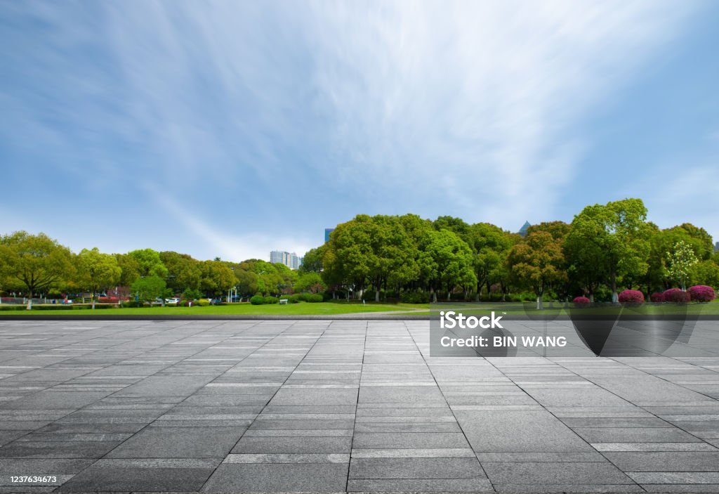 Marble square in front of dense woods of city park under clear sky City Stock Photo