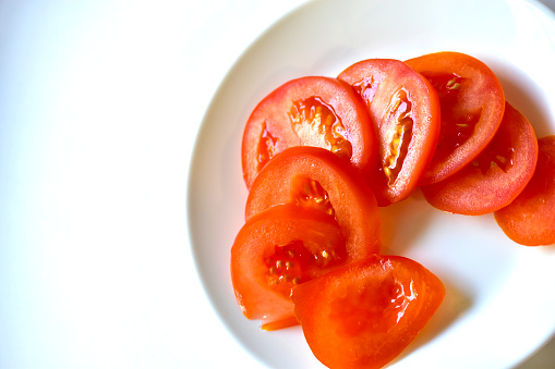 Ripe and juicy tomatoes sliced on a white plate