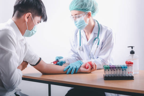 медицинский врач собирает инъекцию шприца образца крови от пациента мужского пола в лабораторных испытаниях. врач-женщина принимая пациен - sample collection стоковые фото и изображения