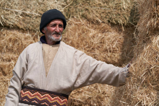 istock Old farmer man with Hay bales on background. Elderly muslim farmer 1237663062