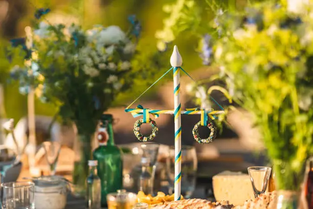 A traditional Swedish maypole decoration on the table at midsummer. Surrounded by food and flowers.