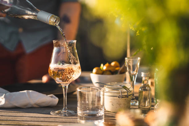 man pouring up rose wine at midsummer dinner - wine imagens e fotografias de stock